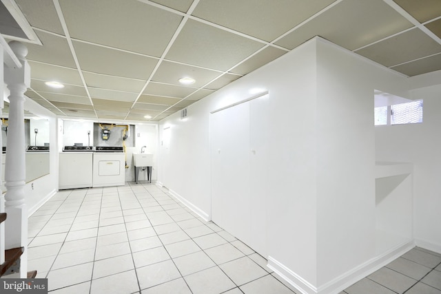 basement with a paneled ceiling, washer and clothes dryer, light tile patterned floors, and sink