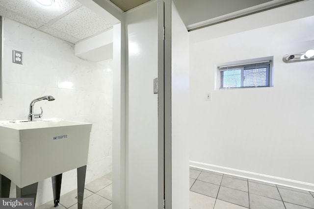 bathroom with tile patterned floors, a paneled ceiling, and tile walls