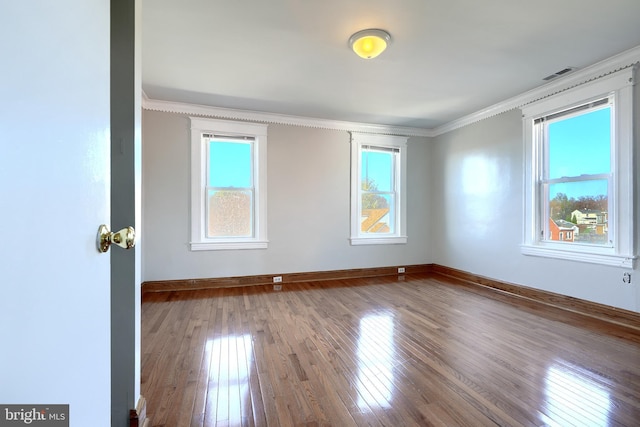 unfurnished room with ornamental molding, hardwood / wood-style flooring, and a healthy amount of sunlight