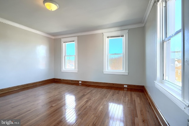 empty room featuring hardwood / wood-style flooring, plenty of natural light, and ornamental molding