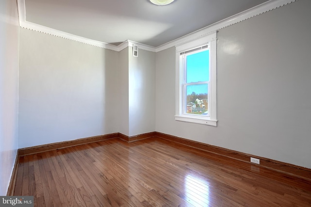 empty room with wood-type flooring and crown molding