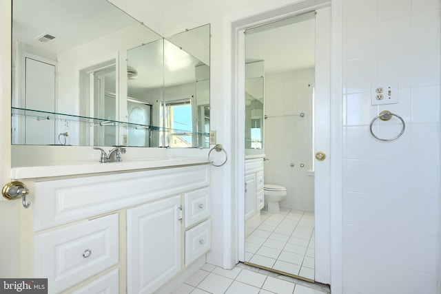 bathroom with tile patterned flooring, vanity, toilet, and tile walls