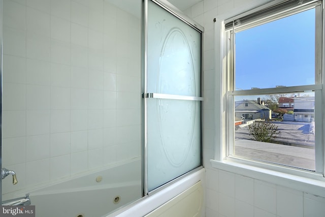 bathroom with a healthy amount of sunlight and bath / shower combo with glass door