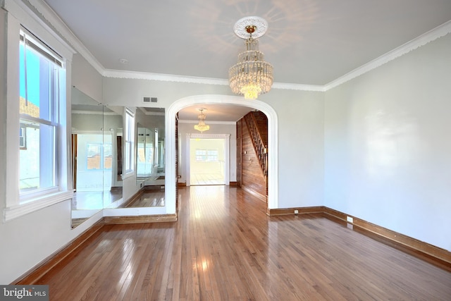 spare room featuring a notable chandelier, wood-type flooring, and ornamental molding