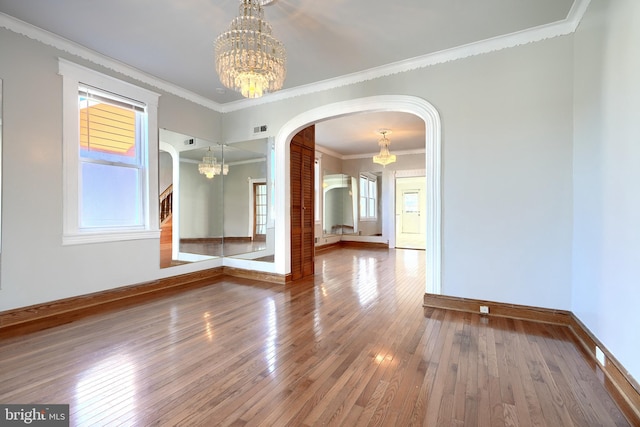 empty room featuring hardwood / wood-style floors, crown molding, and a wealth of natural light