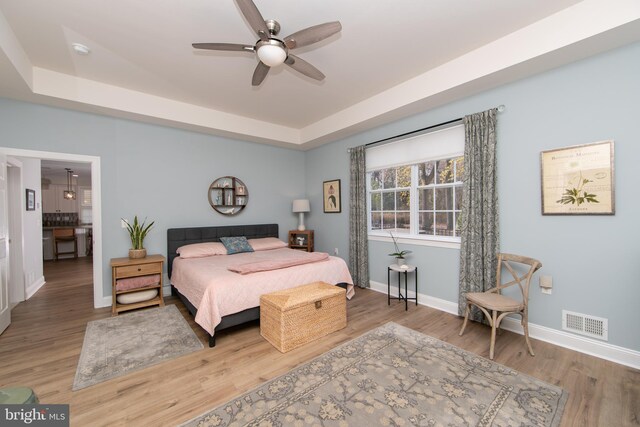 bedroom featuring hardwood / wood-style flooring, ceiling fan, and a tray ceiling