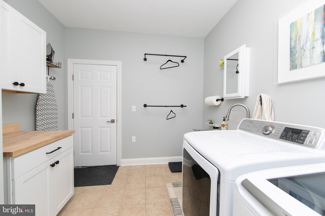 washroom with cabinets, light tile patterned floors, and washing machine and clothes dryer