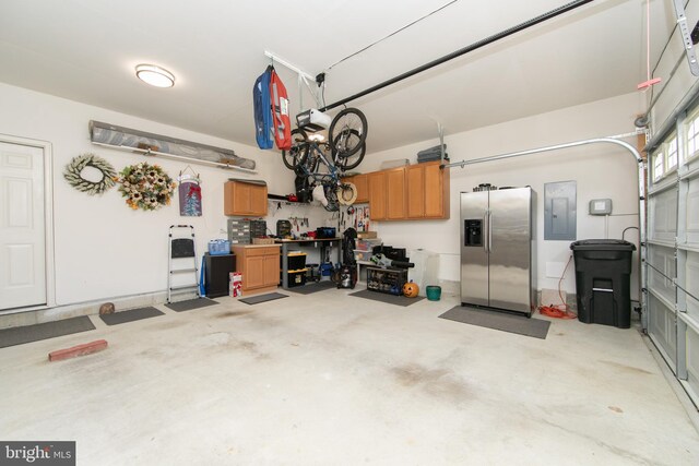 garage featuring electric panel and stainless steel fridge with ice dispenser