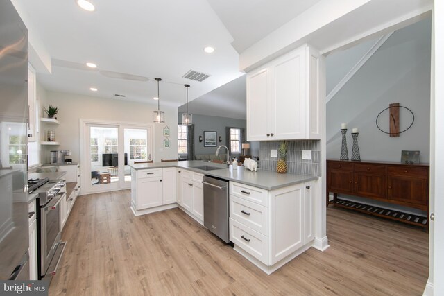 kitchen featuring white cabinets, hanging light fixtures, light hardwood / wood-style floors, kitchen peninsula, and stainless steel appliances