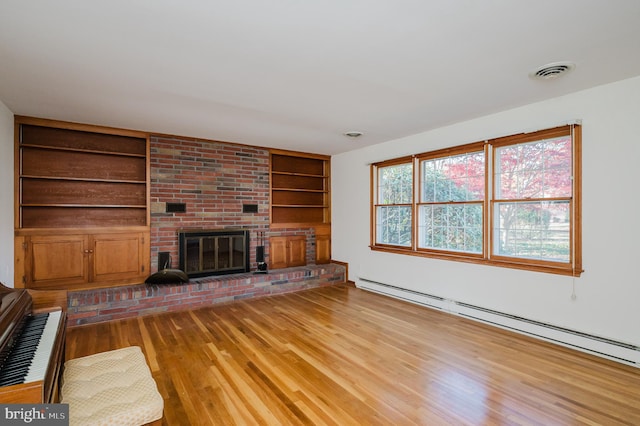 unfurnished living room featuring a fireplace, built in features, a baseboard radiator, and light wood-type flooring