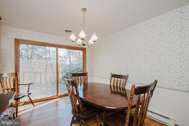 dining room featuring a chandelier, hardwood / wood-style floors, and a baseboard heating unit