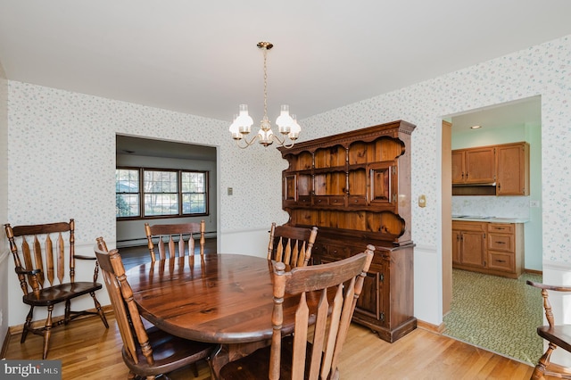 dining room with light wood-type flooring, a baseboard radiator, and an inviting chandelier