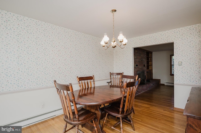 dining area featuring dark wood-type flooring, a fireplace, a chandelier, and a baseboard heating unit