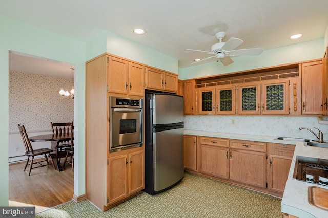 kitchen featuring appliances with stainless steel finishes, sink, light hardwood / wood-style floors, and ceiling fan with notable chandelier