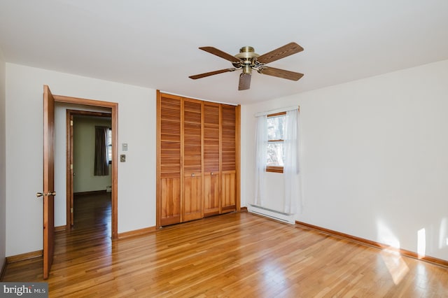 unfurnished bedroom featuring ceiling fan, a baseboard radiator, a closet, and light hardwood / wood-style flooring