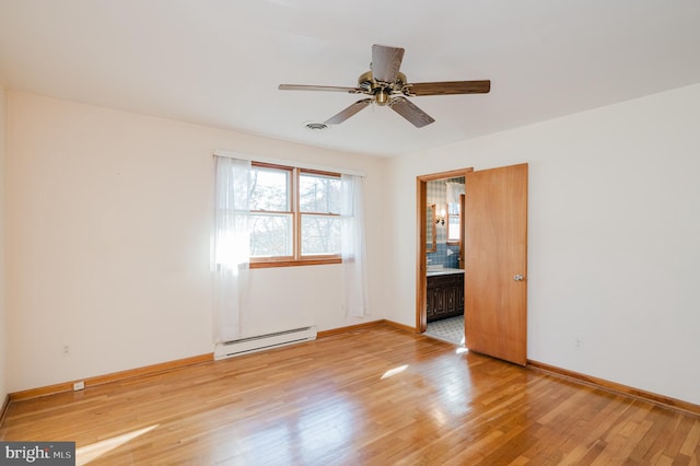 empty room featuring ceiling fan, wood-type flooring, and a baseboard heating unit