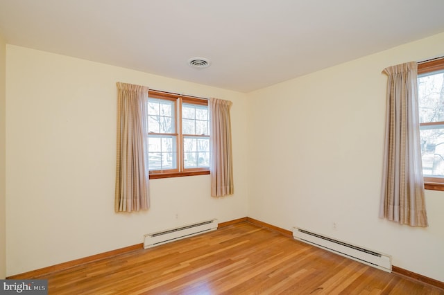 empty room with light hardwood / wood-style floors and a baseboard radiator