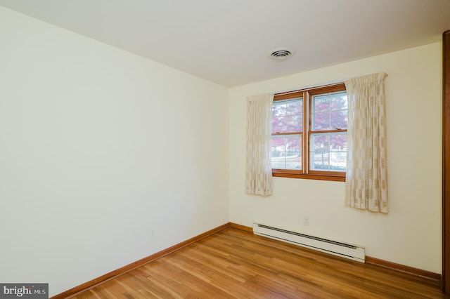 unfurnished room featuring hardwood / wood-style floors and baseboard heating