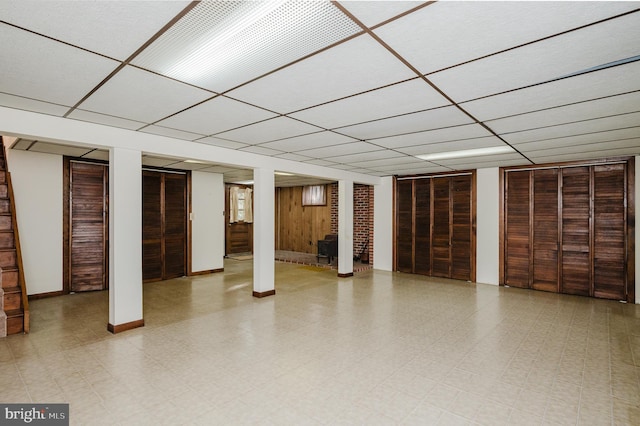 basement featuring wood walls and a paneled ceiling