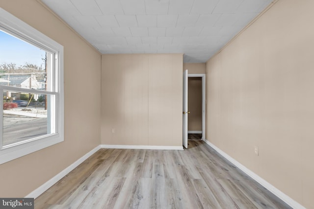 unfurnished room with light wood-type flooring and crown molding