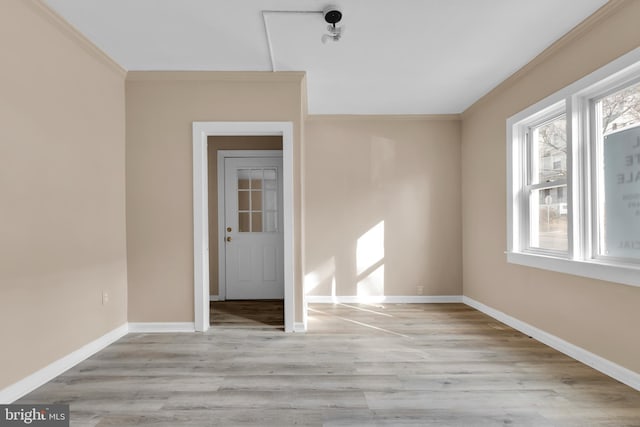 empty room featuring light wood-type flooring and crown molding