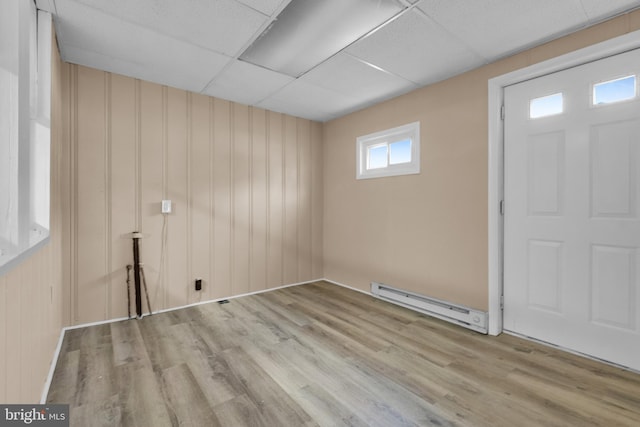 entryway featuring a paneled ceiling, light wood-type flooring, a baseboard heating unit, and wood walls