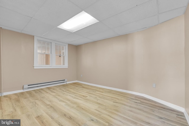 interior space with light wood-type flooring, a baseboard radiator, and a drop ceiling