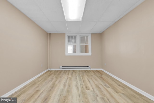 spare room with light wood-type flooring, a drop ceiling, and baseboard heating