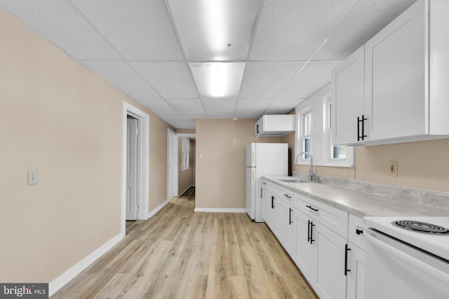 kitchen with a paneled ceiling, white appliances, sink, white cabinets, and light hardwood / wood-style floors