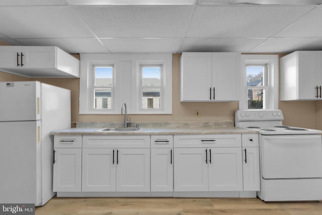 kitchen featuring white cabinetry, sink, a healthy amount of sunlight, and white appliances