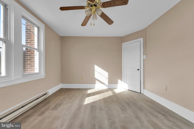 spare room featuring light wood-type flooring, ceiling fan, and a baseboard heating unit