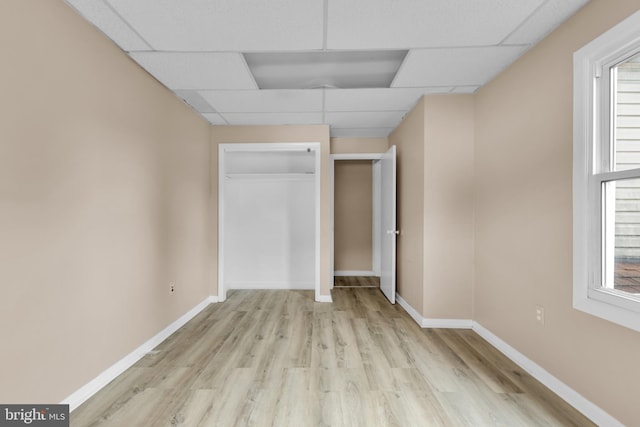 unfurnished bedroom with a paneled ceiling, light hardwood / wood-style flooring, and multiple windows