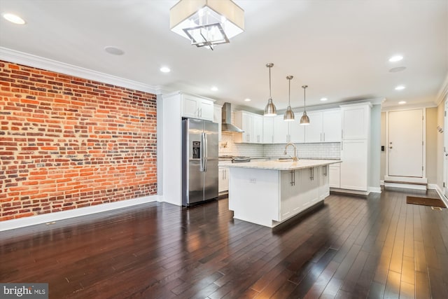 kitchen with wall chimney range hood, stainless steel fridge with ice dispenser, dark hardwood / wood-style floors, pendant lighting, and an island with sink