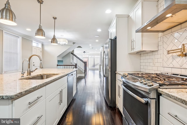 kitchen with dark hardwood / wood-style flooring, white cabinetry, wall chimney range hood, and appliances with stainless steel finishes