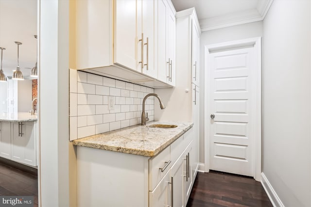 kitchen featuring light stone counters, crown molding, dark hardwood / wood-style flooring, sink, and white cabinets