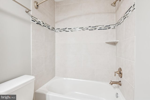 bathroom with tiled shower / bath combo and toilet