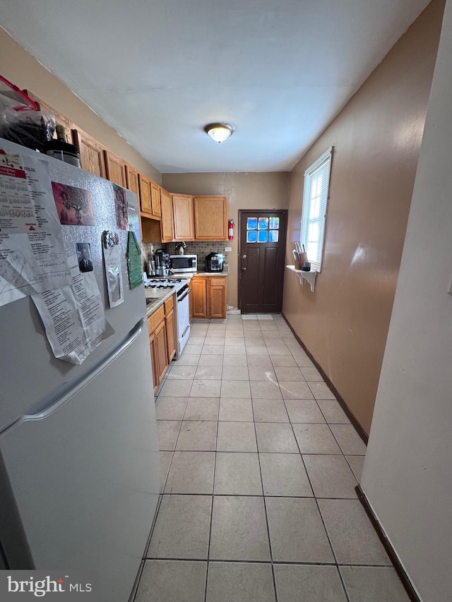 kitchen with decorative backsplash, light tile patterned floors, and white appliances