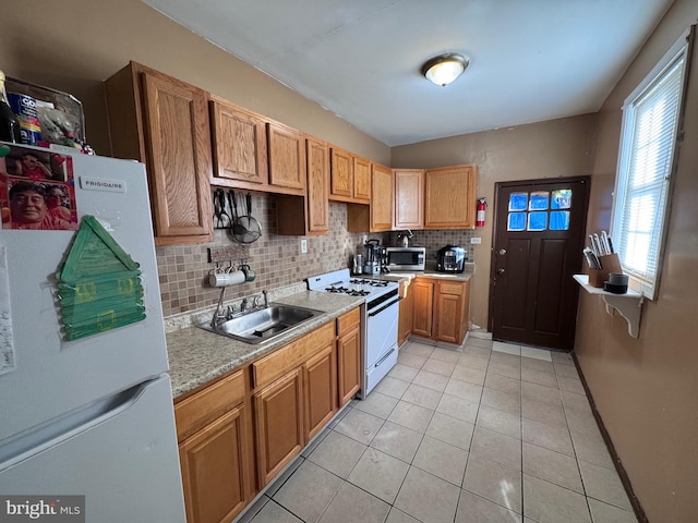 kitchen featuring decorative backsplash, sink, white appliances, and light tile patterned floors