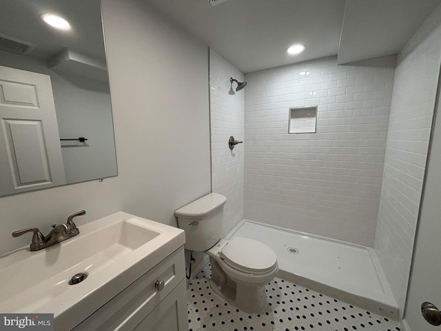 bathroom with vanity, toilet, and a tile shower