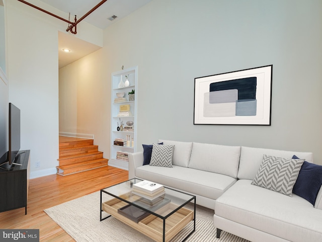 living room with built in shelves and hardwood / wood-style flooring