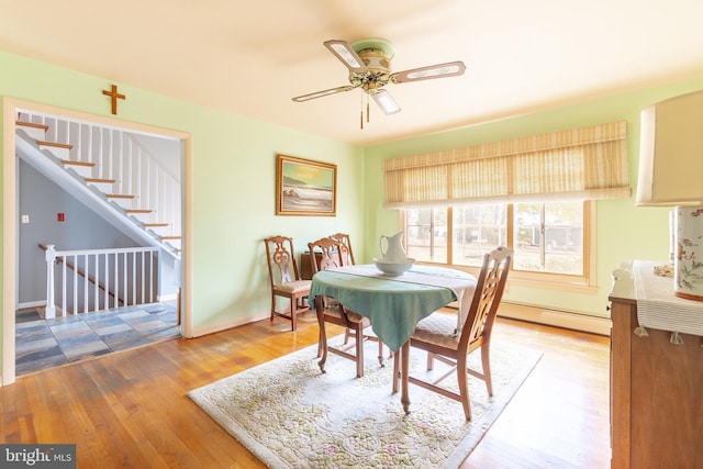 dining space with ceiling fan, hardwood / wood-style floors, and a baseboard heating unit