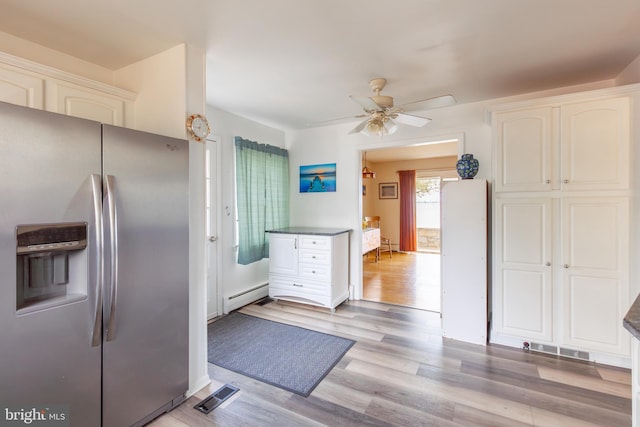 kitchen featuring light hardwood / wood-style flooring, ceiling fan, stainless steel fridge, a baseboard radiator, and white cabinetry