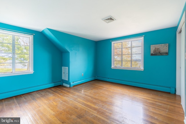 bonus room with plenty of natural light, a baseboard heating unit, and light wood-type flooring