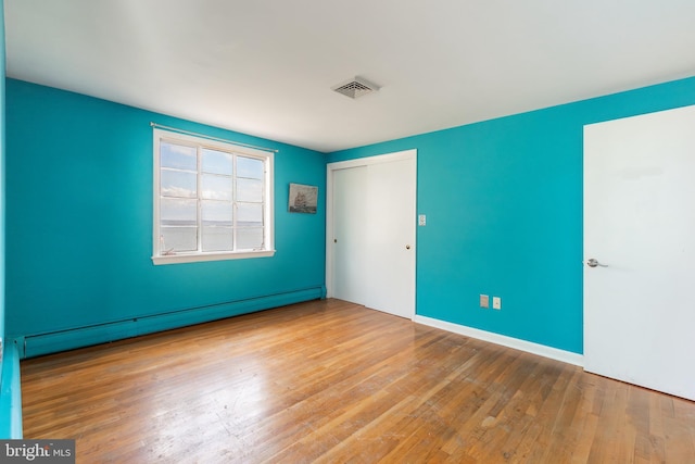 unfurnished room with a baseboard radiator and light hardwood / wood-style flooring