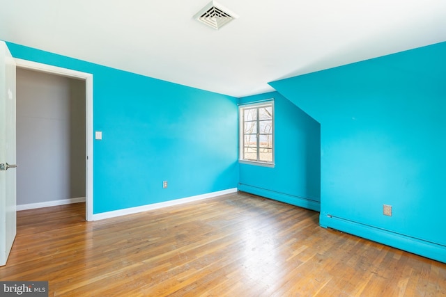 additional living space with wood-type flooring and a baseboard radiator