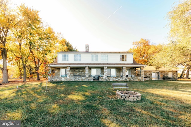 view of front of property featuring a front yard, a porch, and an outdoor fire pit