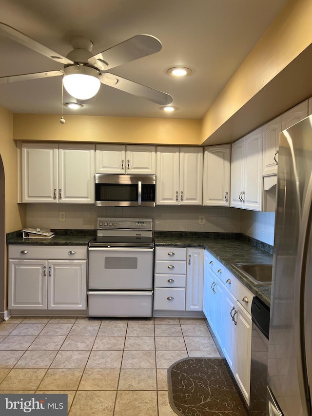 kitchen with white cabinetry, appliances with stainless steel finishes, light tile patterned floors, and backsplash