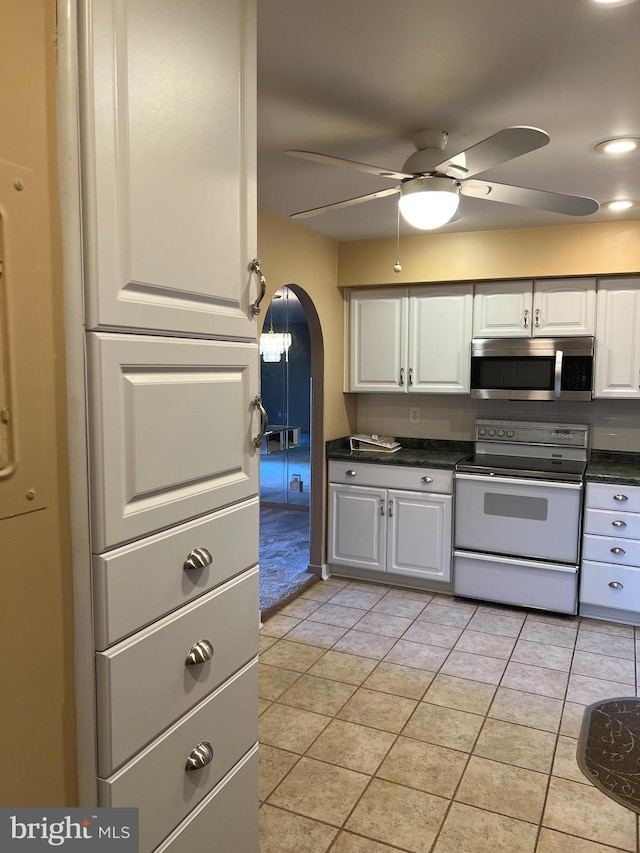 kitchen featuring white range with electric cooktop, backsplash, white cabinetry, light tile patterned floors, and ceiling fan