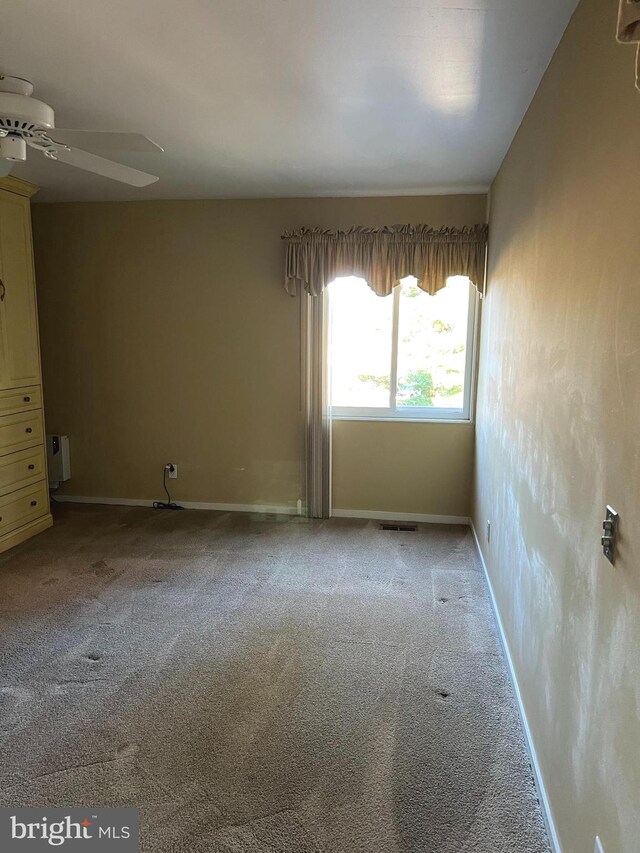 empty room featuring ceiling fan and carpet