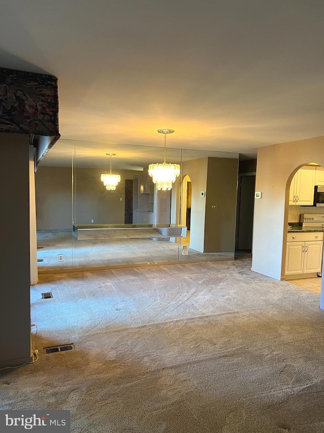 carpeted empty room featuring an inviting chandelier